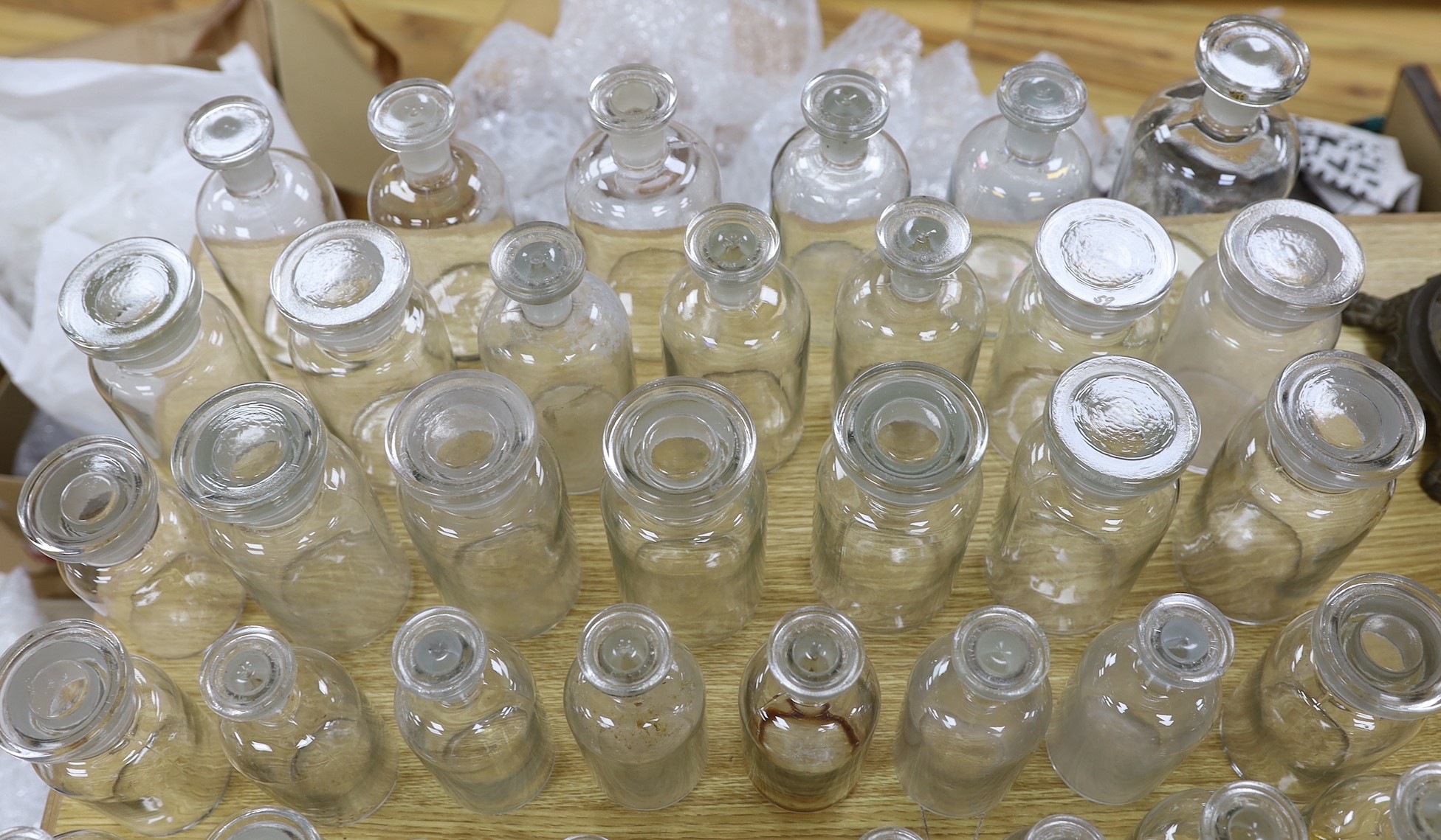 A large collection of clear glass chemist's bottles